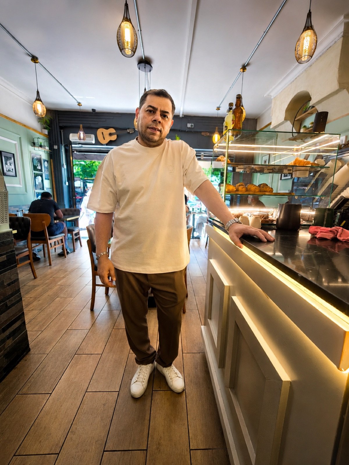 Sam, owner of Rendezvous Caffe, standing beside the counter inside the cafe